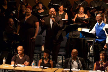 A group of people singing while others sit on chairs